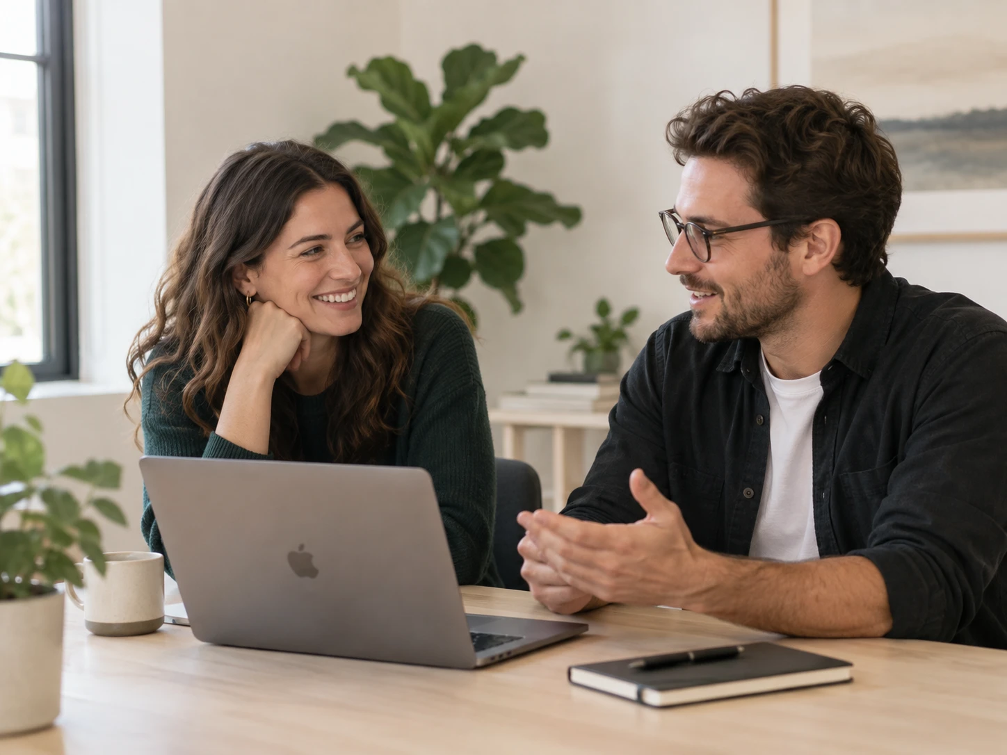Two people at a desk looking at a pitch page together on a laptop.